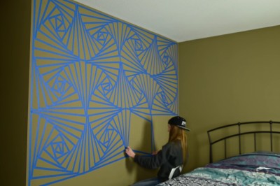  Całą ścianę okleja taśmą malarską i zaczyna malować! Gdy zrywa taśmę efekt jest niesamowity!