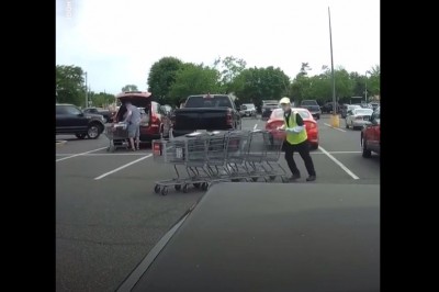 Pracownik marketu z wózkami kontra samochody na parkingu 