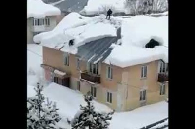 Dwóch specjalistów od odśnieżania dachu w trakcie pracy