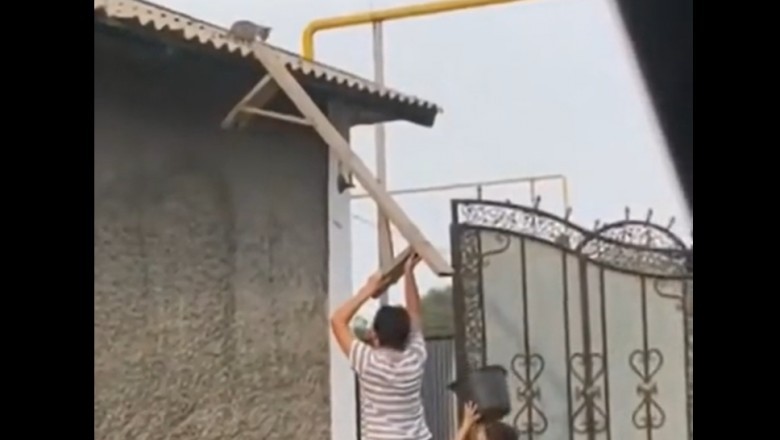 Ratowanie kota na dachu za pomocą wiadra i ławki przez dwóch chłopców